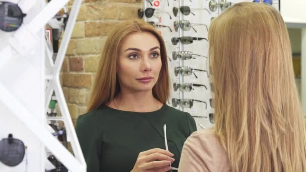 Молода красива жінка намагається сонцезахисні окуляри купувати зі своїм другом — стокове відео