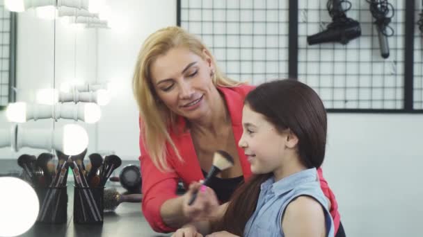 Gelukkig mooie vrouw make-up toe te passen op haar schattige dochter — Stockvideo