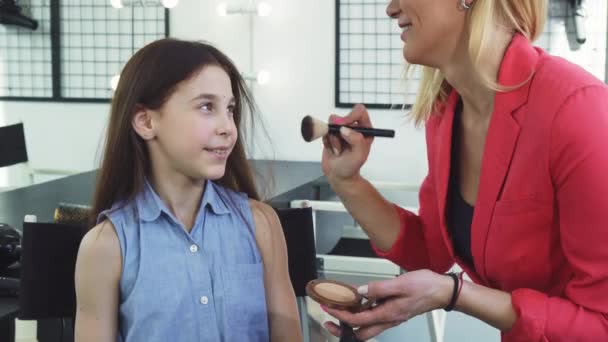 Menina feliz sorrindo enquanto sua mãe aplicando maquiagem em seu rosto — Vídeo de Stock