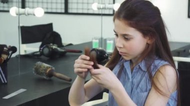 Küçük şirin kız üzgün zarar görmüş saçları split uçları ile inceleyerek arıyorsunuz