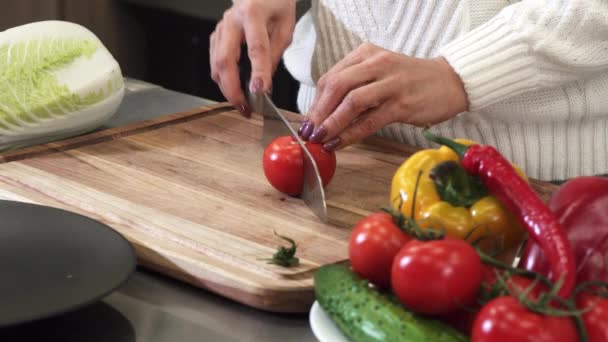 Close up cropped shot of a woman slicing tomato on a wooden cutting board — Stock Video