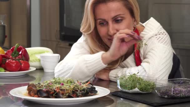 Чудова зріла жінка прикрашає смачну їжу на своїй кухні — стокове відео