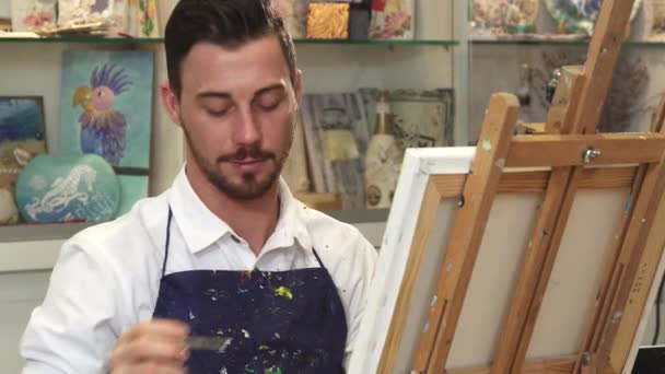 Bonito artista masculino barbudo trabalhando em uma pintura em seu estúdio de arte — Vídeo de Stock