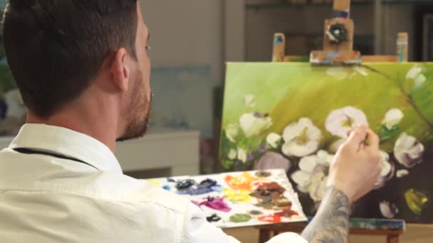 Bakifrån skott av en manlig konstnär som arbetar på en målning på hans Art Studio — Stockvideo