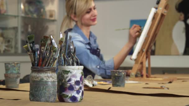 Foco seletivo em um monte de pincéis artista feminina trabalhando em sua pintura — Vídeo de Stock