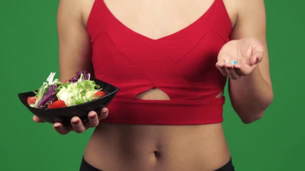 Cropped shot of a woman choosing between salad and vitamins in pills — Stock Video