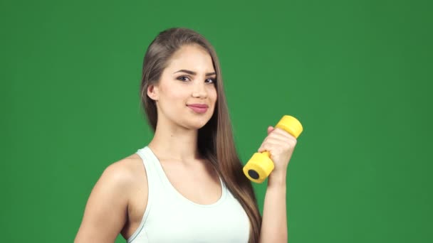 Happy beautiful sportswoman holding dumbbell and a bottle of water smiling — Stock Video
