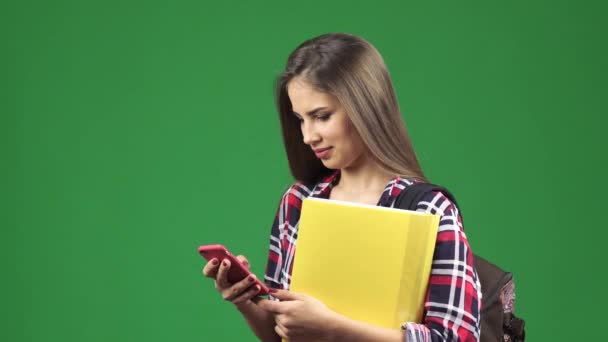 Atractiva joven estudiante usando su teléfono inteligente sonriendo a la cámara — Vídeo de stock