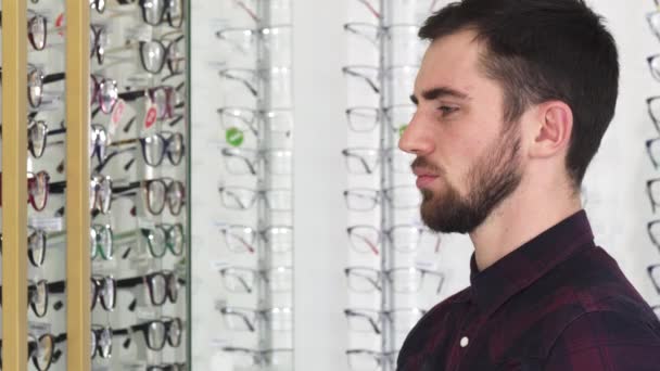 Молодой человек фотографирует очки в магазине очков — стоковое видео
