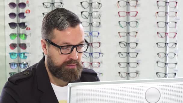 Optometrista maduro trabajando en una computadora en su tienda — Vídeo de stock
