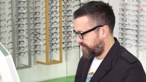 Optometrista profesional trabajando en una computadora en su tienda — Vídeos de Stock