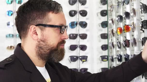 Primer plano de un hombre maduro examinando gafas para la venta en la pantalla — Vídeos de Stock