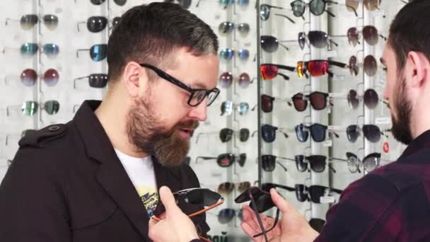 Optometrista profesional mostrando gafas para la venta a su cliente masculino — Vídeo de stock