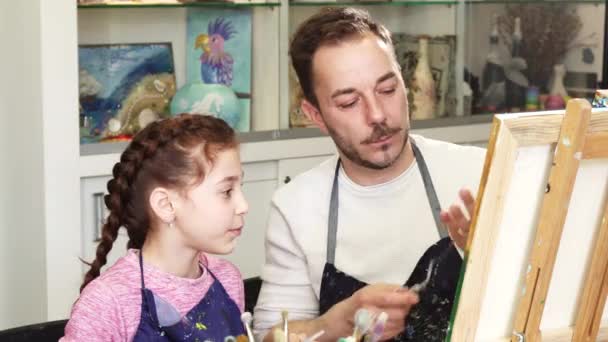 Petite fille mignonne regardant son père artiste peindre une image — Video