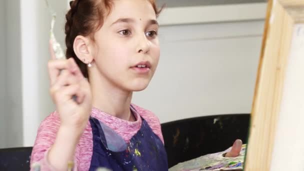 Крупный план красивой маленькой девочки, держащей палетку, рисующей картину — стоковое видео