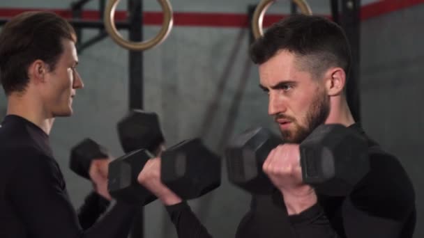 Gros plan d'un beau bodybuilder barbu pompant du fer à repasser à la salle de gym — Video