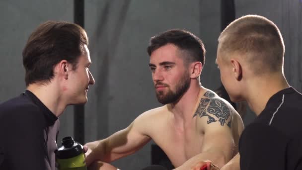Τρεις άνδρες φίλοι αναπαύεται στο γυμναστήριο μετά από γέλια και ομιλίες — Αρχείο Βίντεο