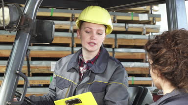 Genç bir kadın fatory işçi forklift onun meslektaşım için konuşmak depolama, işletim