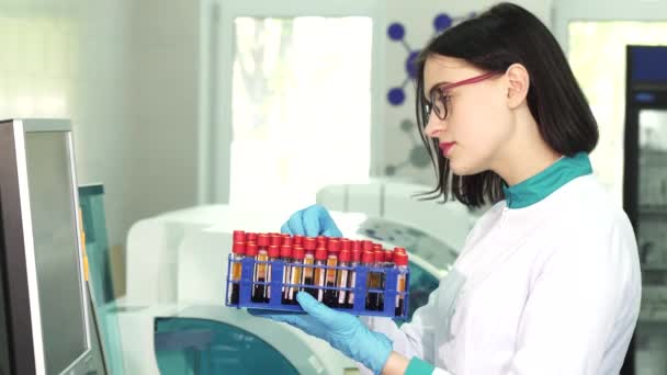 若い女性科学者の血液サンプルのテスト チューブを調べる — ストック動画
