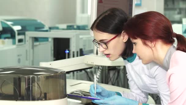 Close up of two female biologists making notes while conducting experiments — Stock Video