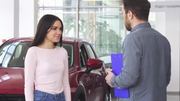 Preciosa mujer feliz estrechando la mano con concesionario de coches después de recibir las llaves del coche — Vídeo de stock
