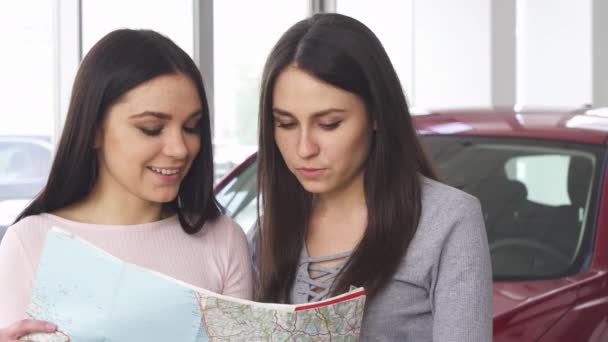 Two beautiful female friends looking for destination on a map