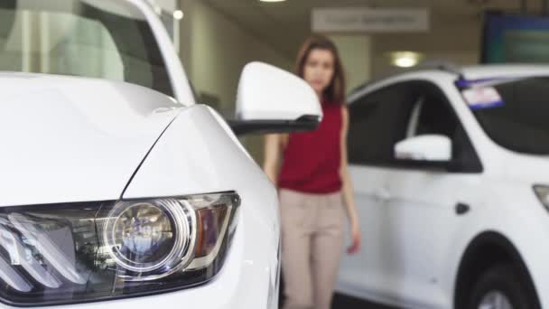 Cliente feminino examinando carro novo no revendedor — Vídeo de Stock