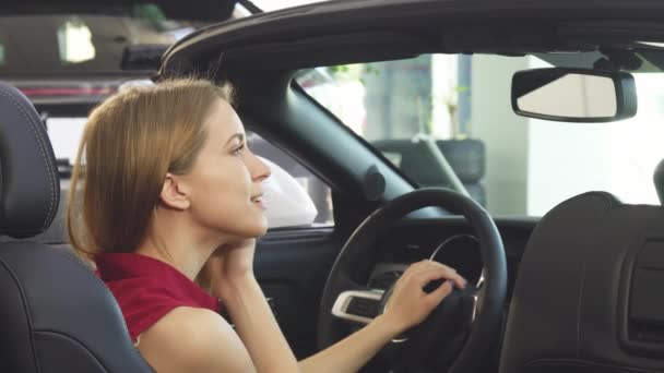 Потрясающая молодая женщина-водитель радостно улыбается сидя в своем кабриолете — стоковое видео