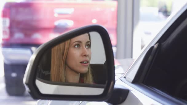 schöne Autofahrerin lächelt in die Kamera im Seitenspiegel