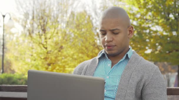 Afro-americano trabalhando em laptop no parque local no outono — Vídeo de Stock