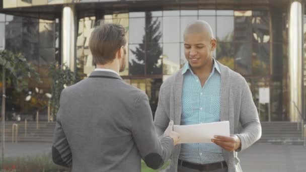 Guapo joven empresario estrechando la mano con su colega al aire libre — Vídeo de stock