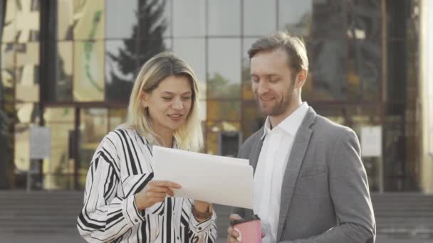 Madura mujer de negocios y su colega masculino examinando documentos al aire libre — Vídeo de stock