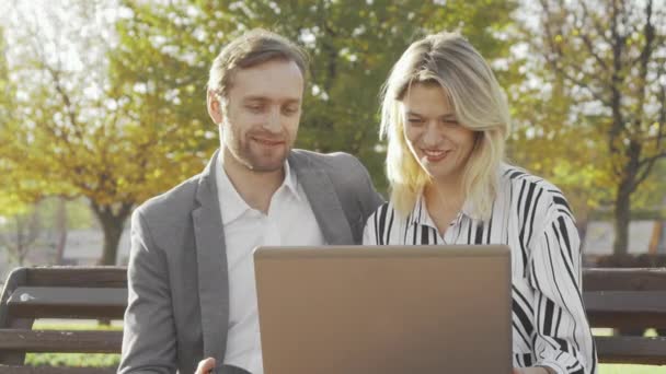 Deux collègues d'affaires utilisant un ordinateur portable au parc ensemble — Video