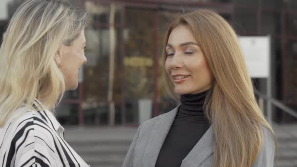 Две женщины-коллеги с радостью разговаривают на открытом воздухе — стоковое видео