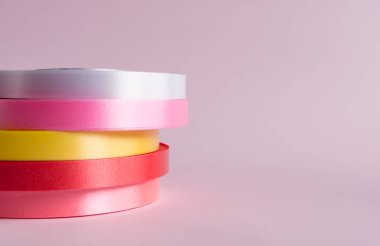 Pembe arkaplanda renkli kurdele rulosu 