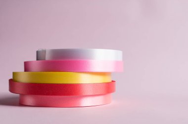 Pembe arkaplanda renkli kurdele rulosu 