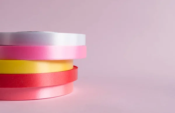 Pembe arkaplanda renkli kurdele rulosu 