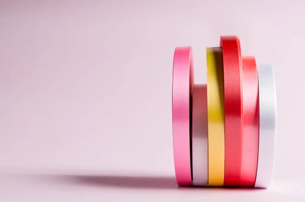 Pembe arkaplanda renkli kurdele rulosu 