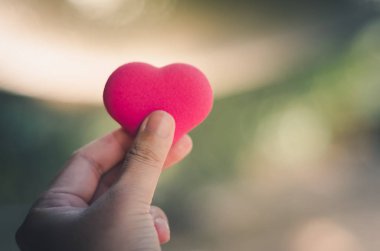 Asyalı adamın elleri pembe kalp şeklinde kabarcık tutuyor.