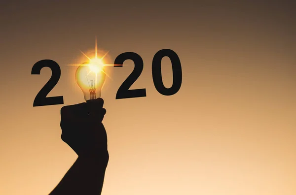2020 Yeni Yıl kutlamaları insan elinin bir kısmı ampulü tutarken