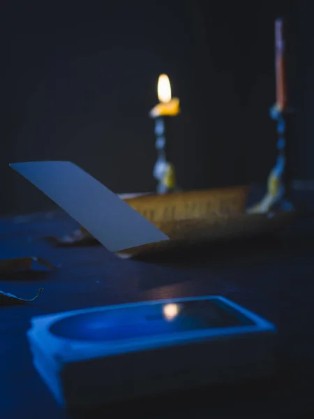Low Key still life photography, floating blank tarot card on the table in dark tone with light from candlestick