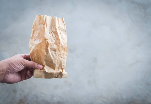 man hand holds used paper bag