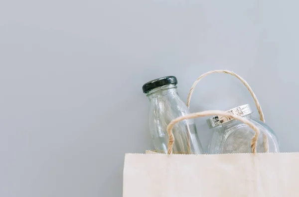 Gri arkaplanda kese kağıdı ve cam eşyalar, plastik paket yok, sıfır atık kavramı