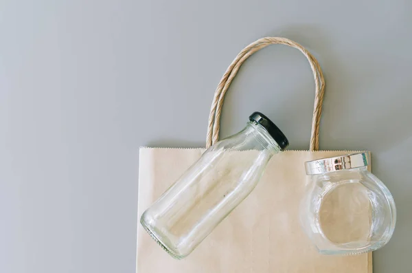 Gri arkaplanda kese kağıdı ve cam eşyalar, plastik paket yok, sıfır atık kavramı