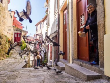 Porto, Portekiz - 12 Şubat 2018: yaşlı bayanı evine eski şehir Porto, Portekiz önünde güvercin besleme, 