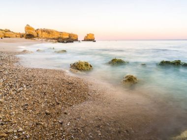 güzel kayalık Sao Rafael Beach'te günbatımı zamanı Portekiz Algarve bölgesinde temiz mavi su ile. 