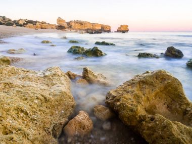 güzel kayalık Sao Rafael Beach'te günbatımı zamanı Portekiz Algarve bölgesinde temiz mavi su ile. 