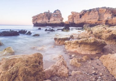 güzel kayalık Sao Rafael Beach'te günbatımı zamanı Portekiz Algarve bölgesinde temiz mavi su ile. 