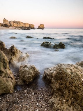 güzel bir kayalık Sao Rafael plaj günbatımı zamanı, Portekiz Algarve bölgesinde temiz mavi su ile. 