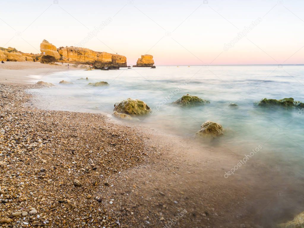 beautiful rocky Sao Rafael beach in sunset time with clean blue water in Algarve region, Portugal. 